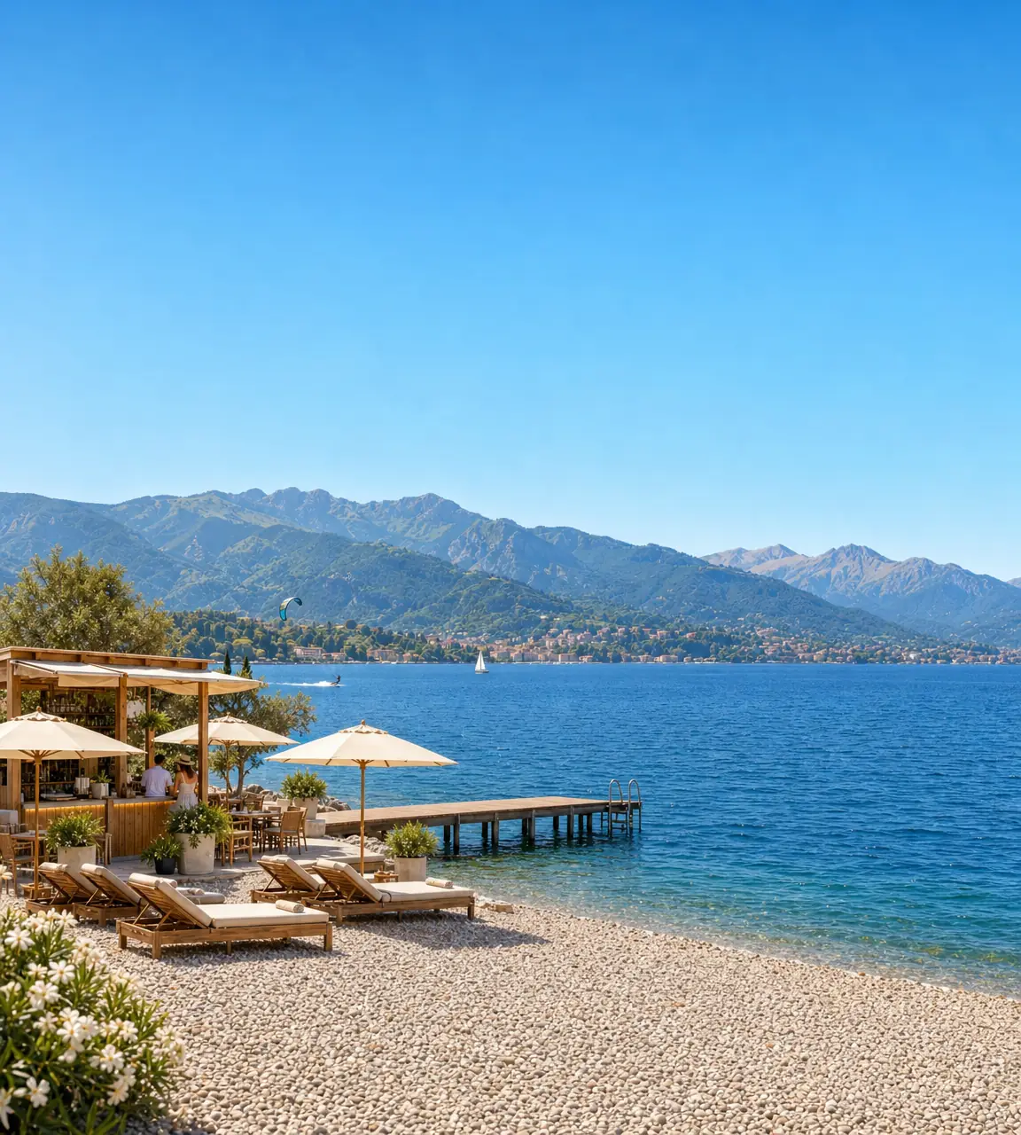 Un lido su un lago, con sdraio e ombrelloni sulla riva e le montagne sullo sfondo